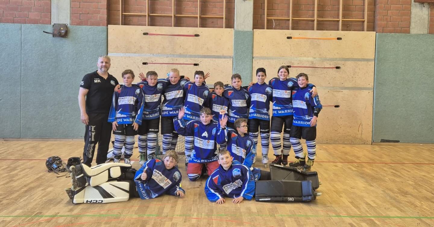 Der zweite Ligaspieltag in der Schülerliga u-13 fand am Sonntag in Lüneburg statt. Die Vfl Jade Warriors traten gegen den amtierenden Meister, die Empelde Maddogs und gegen die Salzstadtkeiler aus Lüneburg an.

Direkt die erste Partie gegen Empelde hatte es in sich. Empelde mit viel Druck vom ersten Bulli weg. Doch es waren die Jadestädter, die zwei ihrer drei Torschüsse durch Anton Stindt und Victoria Liepold im gegnerischen Gehäuse unterbrachten. Empelde davon aber unbeeindruckt, weiter mit vielen Chancen und glichen dann verdient vor der Halbzeit zum 2:2 aus.

Dierkt nach Wiederanpfiff wurden die Warriors durch einen Doppelpack kalt erwischt, 2:4 für Empelde. Carlo Liepold antwortete zwar per Alleingang aus der eigenen Hälfte mit dem Anschluss, doch dann hagelte es viele Strafzeiten gegen die Warriors und Empelde nutzten ihre Chancen eiskalt in Überzahl. Torhüter Matti Karsjens machte Platz für Jakob Krah, der noch etwas Spielpraxis bekam, aber die 3:7 Niederlage auch nicht mehr abwehren konnte.

Nach nur kurzer Pause hieß es, Kräfte mobilisieren, Kopf hoch und versuchen im zweiten Spiel des Tages zu punkten.

Die heimischen Salzstadtkeiler aus Lüneburg erwischten einen Blitzstart, nach nur 22 Sekunden stand es 0:1. Doch nur 30 Sekunden später, stand Kalle Meschke goldrichtig vor dem generischen Goalie und nutzte einen Abstauber nach Vorlage von Stindt zum Ausgleich. Durch eine Unachtsamkeit der Warriors ging Lüneburg nochmals in Führung, ehe das Geschwister Duo Liepold doppelt traf und Joel Matyjascyk den Pausenstand auf 4:2 ausbaute. Im zweiten Abschnitt wechselten die Goalies nochmals ihren Platz im Tor, wieder kam Krah für Karsjens, der bis zum Schluss ohne Gegentor blieb. Seine Vorderleute Victoria Liepold und Oskar Boltjes erzielten durch gutes Passspiel mit ihrem Kapitän Amin Jelliti noch zwei weitere Tore und sicherten sich die drei Punkte mit einem Endstand von 6:2 Toren.

Bereits am 10.05. findet der nächste Spieltag in Empelde (Hannover) statt. Dort treffen die Warriors wieder auf die Maddogs.